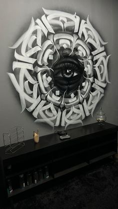 an eye is shown in the center of this artistic wall art piece, which features white letters and black accents