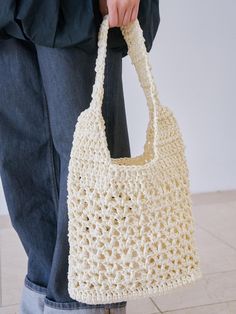 a person holding a crocheted white bag