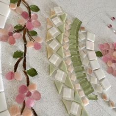 a glass plate with some flowers and leaves on it, next to a mosaic wall hanging