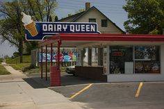 an old dairy queen store on the corner of a street with trees in the background