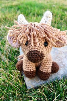 a small stuffed animal sitting on top of a rock in the middle of some grass