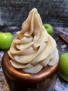 a cupcake with whipped cream and apples in the background