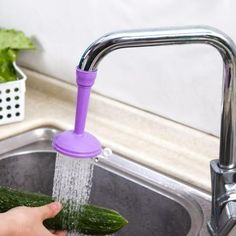 a person washing cucumbers in a sink with water running from the faucet