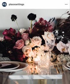 the table is set with candles and flowers on it, along with plates and silverware