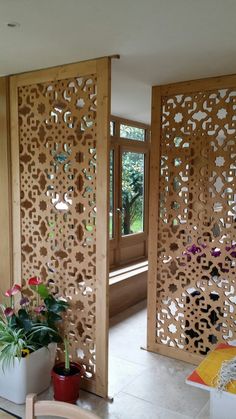 a room divider made out of wood with flowers on the table and potted plants