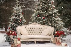 a couch sitting in the middle of a snow covered forest with christmas trees and presents