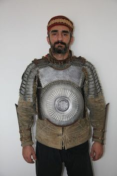 a man dressed in an armor and helmet poses for the camera with his hands on his hips