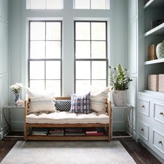 a living room filled with furniture next to a window covered in white pillows and blankets