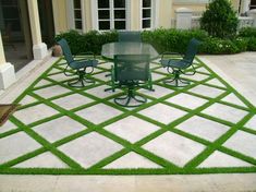 an outdoor patio with green chairs and a table on the grass in front of a house