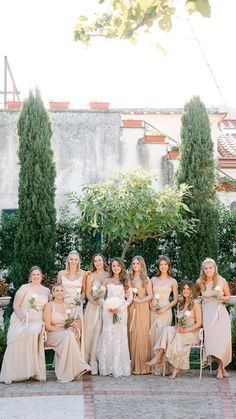 a group of women standing next to each other in front of some bushes and trees