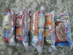 five bags of food are lined up on the floor next to each other, all wrapped in plastic