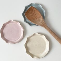 three bowls and two wooden spoons on a white surface