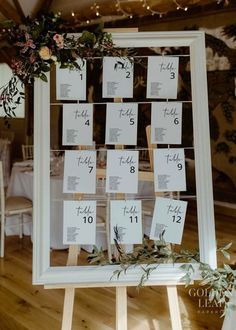 a wooden easer with seating cards and greenery on the top is set up for a wedding reception