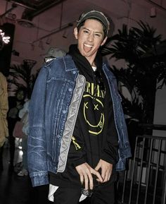 a young man wearing a jean jacket and cap