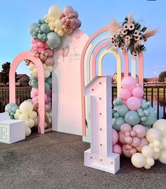 there are many balloons on the ground and in front of an arch that is decorated with flowers