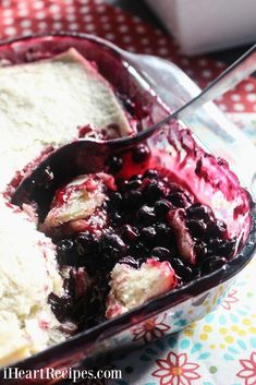 a glass dish filled with ice cream and fruit toppings on top of a table