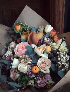 a bouquet of flowers sitting on top of a brown paper wrapped in some kind of wrapping