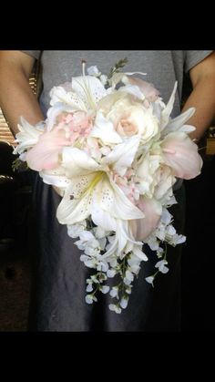 a person holding a bouquet of white and pink flowers in front of their face,