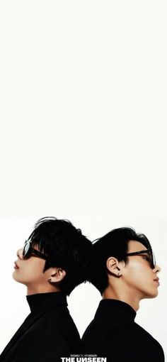 two young men with black hair and glasses are facing each other in front of a white background