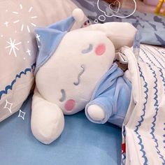 a white stuffed animal laying on top of a bed next to pillows and pillow cases