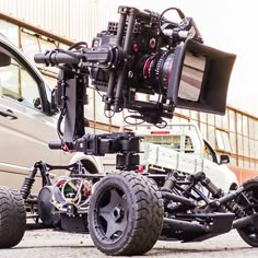 a car is parked in front of a vehicle with a large camera attached to it