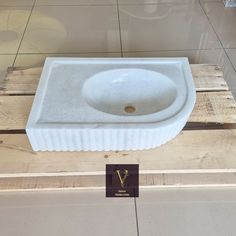 a white sink sitting on top of a wooden pallet next to a tile floor