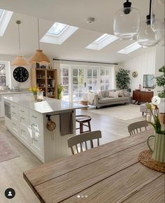 a large open concept kitchen and living room with skylights on the ceiling, dining table in foreground