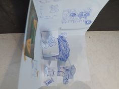 a piece of paper with drawings on it sitting on top of a counter next to a cup