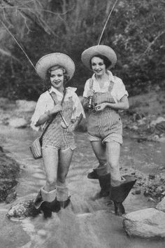 two women in cowboy hats and overalls crossing a stream with their arms around each other