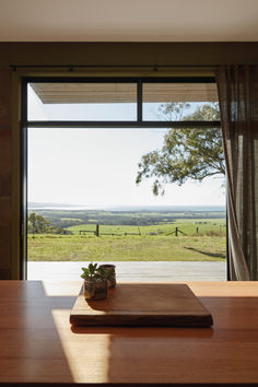 a wooden table with a book on top of it in front of a large window