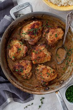 a pan filled with meat and gravy next to rice