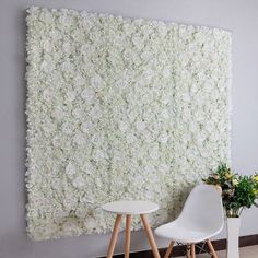 two white chairs are in front of a flower wall