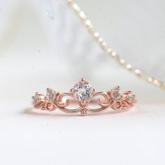 a close up of a diamond ring on a white surface with pearls in the background