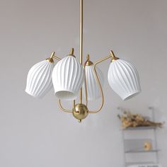 three white lamps hanging from a gold chandelier in a living room or dining room