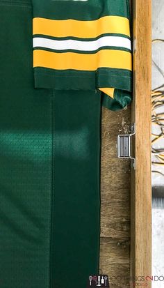 the green and yellow jersey is next to a wooden box with an object in it