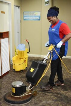 a woman is cleaning the floor with a machine