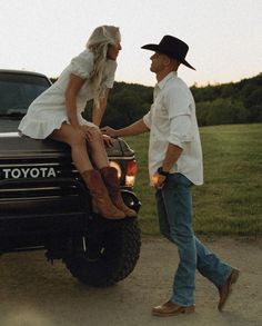 a man and woman are sitting on the back of a pickup truck, talking to each other