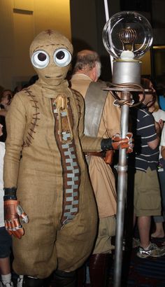 a man dressed in costume standing next to a metal object with googly eyes on it