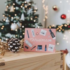 a pink christmas card sitting on top of a wooden table next to a pine cone