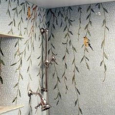 a bathroom with a shower head and shelves on the wall next to it, decorated with leaves