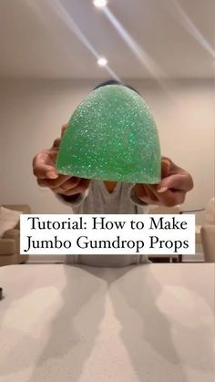 a person holding a green object over their head with the words, how to make jumbo gumdrop props