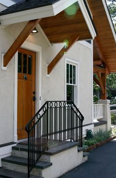 a white house with black railing and wooden door