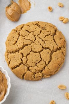 a cookie with peanut butter on it next to a bowl of peanuts and a spoon