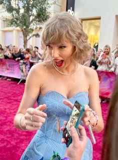 a woman in a blue dress is talking to someone on the red carpet at an event