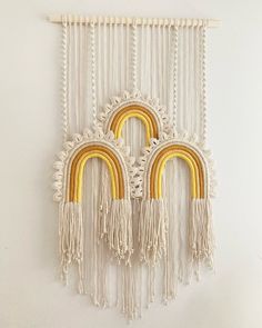 two yellow and white macrame wall hangings with fringed ends, one in the shape of a rainbow