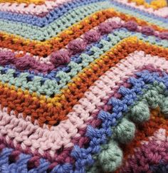 a multicolored crocheted blanket laying on top of a table