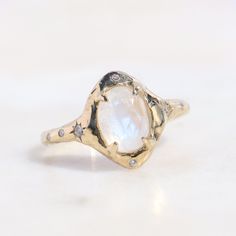 a gold ring with a large white stone in the center and small diamonds around it