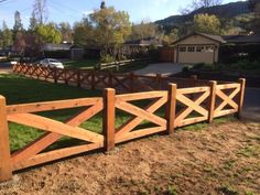 a wooden fence in front of a house with cars parked on the road behind it