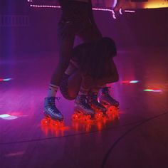 two people riding roller skates on top of a purple and red light filled floor