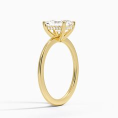 a yellow gold engagement ring with an oval cut diamond on the center and side stones